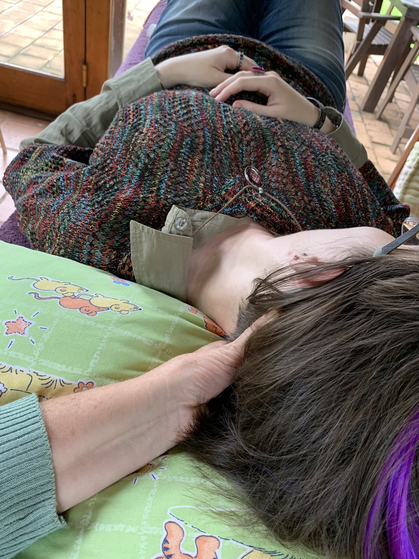 Julia's hands supporting an adult client's head during treatment