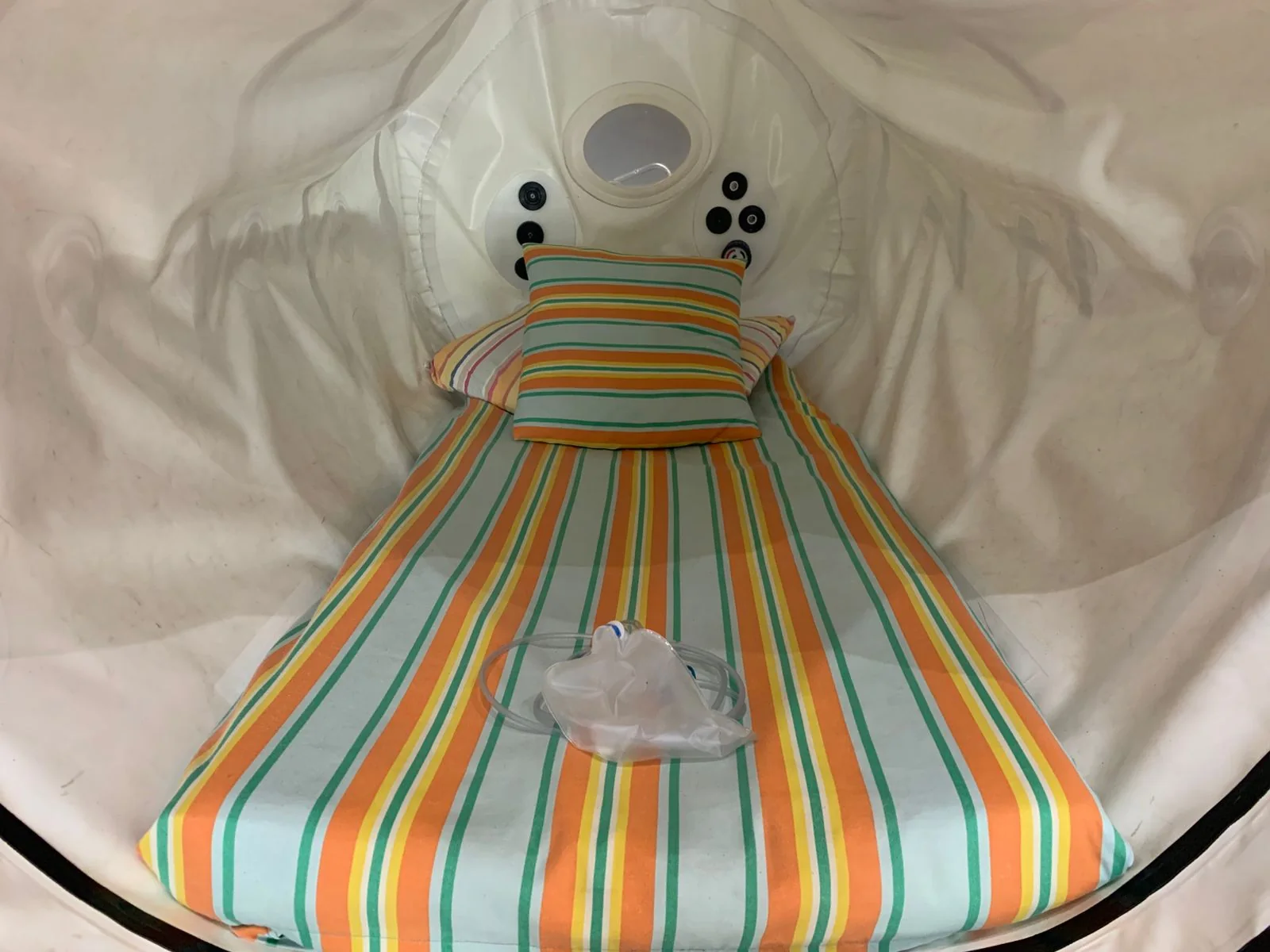 Interior of the mild HBoT chamber prepared with striped bedding and an oxygen mask