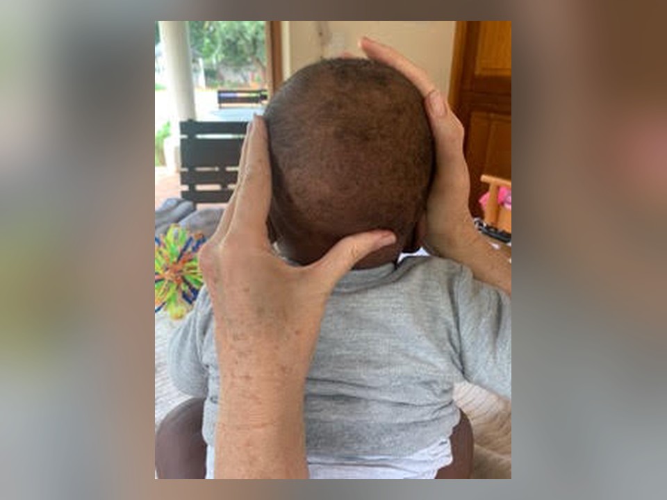 Julia's hands supporting a baby’s head during a CFT session